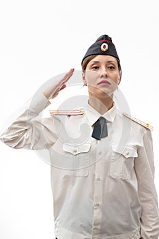 A beautiful young female Russian police officer in dress uniform and a white shirt on a white background salutes the commander.