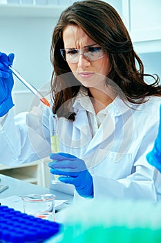 Beautiful young female scientist or researcher working in laboratory with test tube doing some research