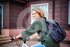 Beautiful young female student in a sweater with backpack on a b