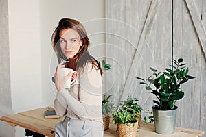 Beautiful young feminine woman relaxing at home in lazy weekend morning with cup of coffee