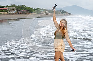 Beautiful young Filipina woman,playfully paddling in the shallow waves of the long sandy beach at Iba,Zambales,Luzon,Philippines