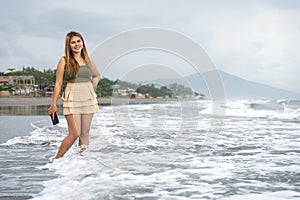 Beautiful young Filipina woman,playfully paddling in the shallow waves of the long sandy beach at Iba,Zambales,Luzon,Philippines