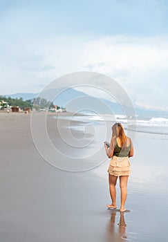 Beautiful young Filipina woman,playfully paddling in the shallow waves of the long sandy beach at Iba,Zambales,Luzon,Philippines