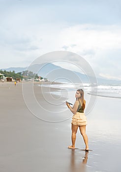 Beautiful young Filipina woman,playfully paddling in the shallow waves of the long sandy beach at Iba,Zambales,Luzon,Philippines.