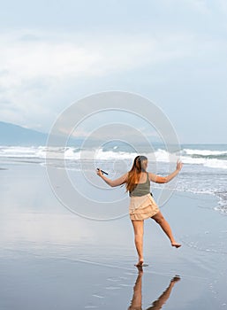 Beautiful young Filipina woman,playfully paddling in the shallow waves of the long sandy beach at Iba,Zambales,Luzon,Philippines