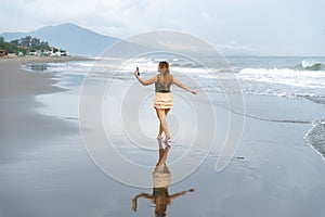 Beautiful young Filipina woman,playfully paddling in the shallow waves of the long sandy beach at Iba,Zambales,Luzon,Philippines