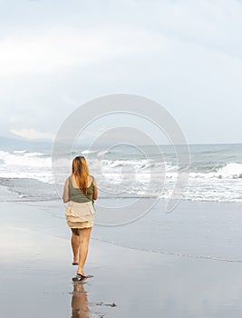 Beautiful young Filipina woman,playfully paddling in the shallow waves of the long sandy beach at Iba,Zambales,Luzon,Philippines