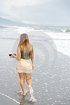 Beautiful young Filipina woman,playfully paddling in the shallow waves of the long sandy beach at Iba,Zambales,Luzon,Philippines