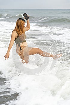 Beautiful young Filipina woman,playfully paddling in the shallow waves of the long sandy beach at Iba,Zambales,Luzon,Philippines