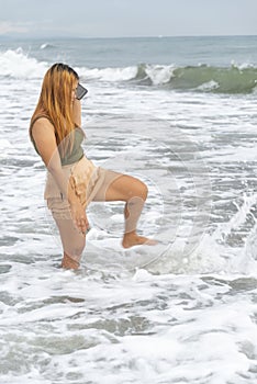 Beautiful young Filipina woman,playfully paddling in the shallow waves of the long sandy beach at Iba,Zambales,Luzon,Philippines