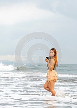 Beautiful young Filipina woman,playfully paddling in the shallow waves of the long sandy beach at Iba,Zambales,Luzon,Philippines