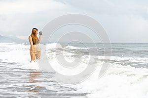 Beautiful young Filipina woman,playfully paddling in the shallow waves of the long sandy beach at Iba,Zambales,Luzon,Philippines