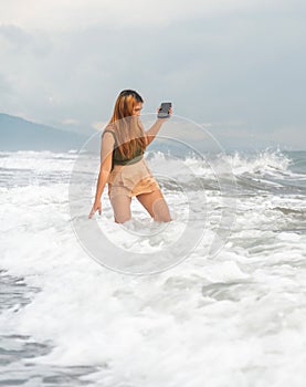 Beautiful young Filipina woman,playfully paddling in the shallow waves of the long sandy beach at Iba,Zambales,Luzon,Philippines