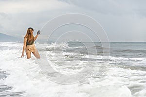 Beautiful young Filipina woman,playfully paddling in the shallow waves of the long sandy beach at Iba,Zambales,Luzon,Philippines