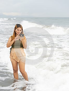 Beautiful young Filipina woman,playfully paddling in the shallow waves of the long sandy beach at Iba,Zambales,Luzon,Philippines