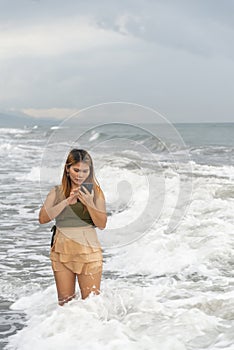 Beautiful young Filipina woman,playfully paddling in the shallow waves of the long sandy beach at Iba,Zambales,Luzon,Philippines