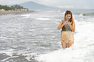 Beautiful young Filipina woman,playfully paddling in the shallow waves of the long sandy beach at Iba,Zambales,Luzon,Philippines