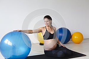 Beautiful, young, fit, athletic and pregnant woman with black hair doing fitness exercises in a modern apartment