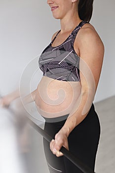 Beautiful, young, fit, athletic and pregnant woman with black hair doing fitness exercises in a modern apartment