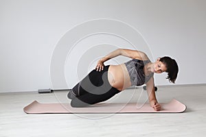 Beautiful, young, fit, athletic and pregnant woman with black hair doing fitness exercises in a modern apartment