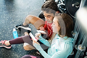 Fit couple in modern crossfit gym with smartphone.