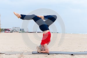 Beautiful young fit woman doing sport exercises, variation of supported headstand posture, salamba sirsasana, side view
