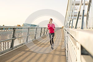 Beautiful young fit woman running on a bridge doing her workout