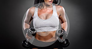 Beautiful young fitness instructor woman posing in studio with weights