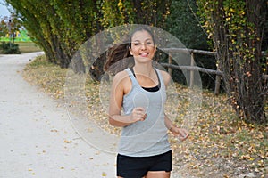 Beautiful young fitness woman running in the park. Smiling girl training outdoors