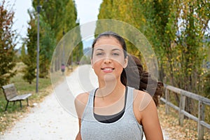 Beautiful young fitness woman running in the park. Smiling girl training outdoors