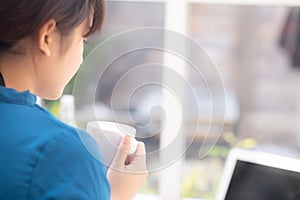 Beautiful young freelance asian woman smiling working and on laptop computer at desk coffee shop with professional