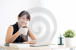 Beautiful young freelance asian woman smiling working and on laptop computer at desk office with professional