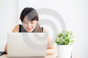 Beautiful young freelance asian woman smiling working and typing on laptop computer at desk office with professional