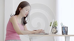 Beautiful young freelance asian woman smiling working and typing on laptop computer at desk office with professional