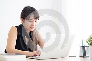 Beautiful young freelance asian woman smiling working and typing on laptop computer at desk office with professional