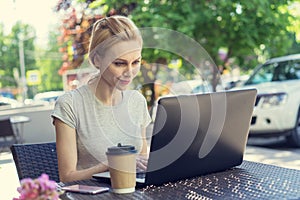 Beautiful young freelancer caucasian woman using laptop computer sitting at cafe. Happy smiling blonde girl working online or stud