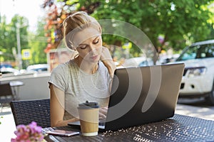 Beautiful young freelancer caucasian woman using laptop computer sitting at cafe. Happy smiling blonde girl working online or stud