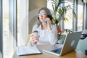 Beautiful Young Freelancer Woman Using Laptop Computer Sitting At Cafe Table. Happy Smiling Girl Working Online Or