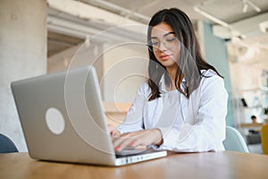 Beautiful Young Freelancer Woman Using Laptop Computer Sitting At Cafe Table. Happy Smiling Girl Working Online Or