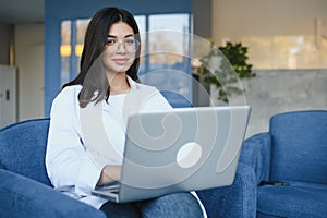 Beautiful Young Freelancer Woman Using Laptop Computer Sitting At Cafe Table. Happy Smiling Girl Working Online Or