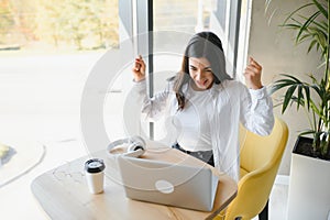 Beautiful Young Freelancer Woman Using Laptop Computer Sitting At Cafe Table. Happy Smiling Girl Working Online Or