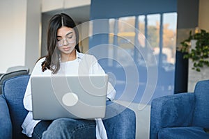 Beautiful Young Freelancer Woman Using Laptop Computer Sitting At Cafe Table. Happy Smiling Girl Working Online Or