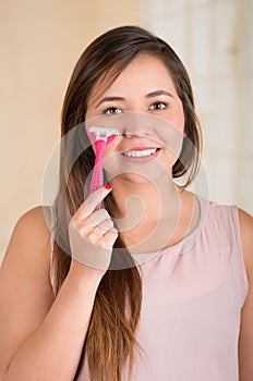 Beautiful young funny woman with an shaver on her face