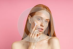 Beautiful young ginger woman with cream on face photo