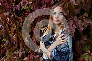 Beautiful young girl in the autumn foliage walks through the city streets on a sunny afternoon in a coat and a warm jacket