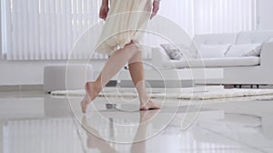 Beautiful young girl bare feet moving on interior in the living room in slow motion. View of young girl elegantly to