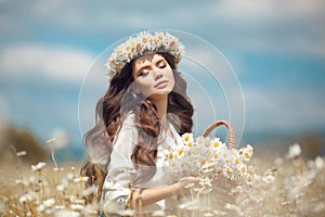 Beautiful young girl with basket of flowers over chamomile field. Carefree happy brunette woman with healthy wavy hair having fun