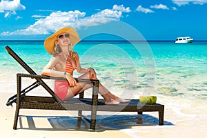Beautiful young girl in bikini is sitting on a sun lounger coast