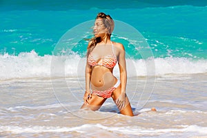 Beautiful young girl in bikini on a tropical beach. Blue sea in