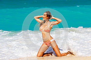 Beautiful young girl in bikini on a tropical beach. Blue sea in